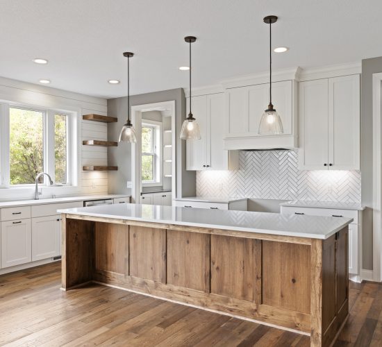 Farmhouse kitchen with wood island and white cabinets and herringbone tile backsplash