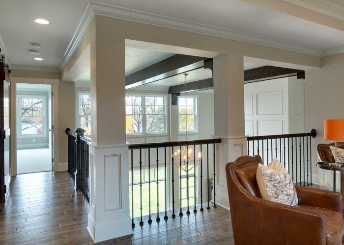 Black railing on upper level of home with exposed beam ceiling