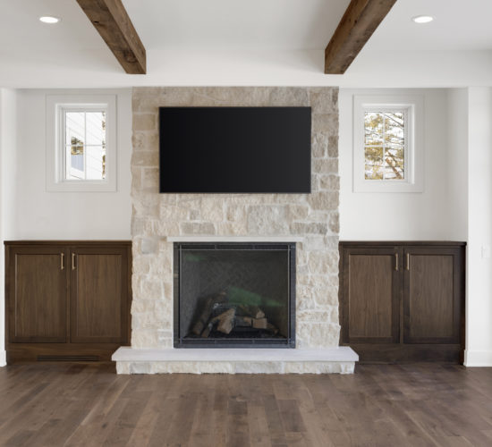 great room with stone fireplace, built-ins, beamed ceiling