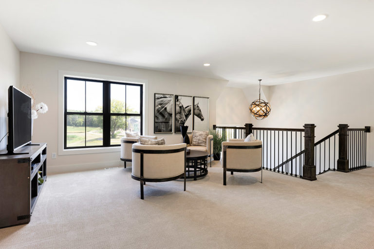 Upstairs living space with cream lounge chairs and television
