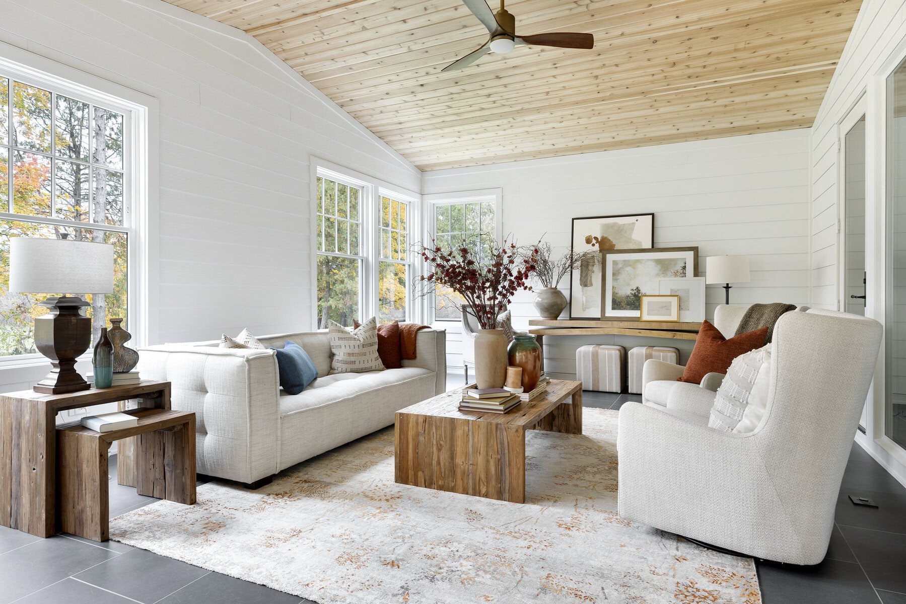Open living room with large windows. White and wood decor
