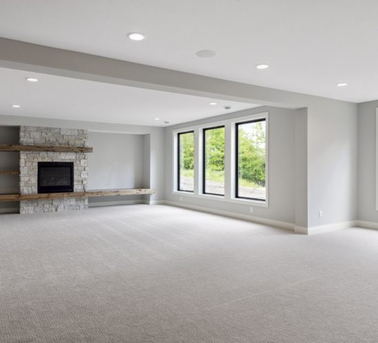 lower level rec room with stone fireplace and floating shelves